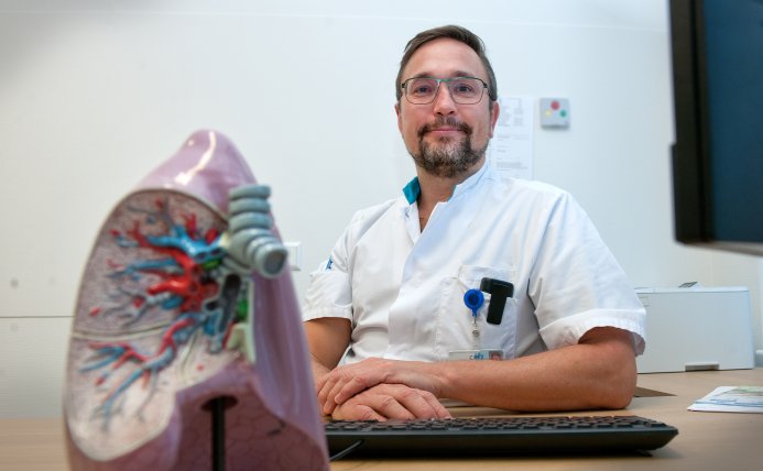 Michiel Spanbroek achter zijn bureau, een model van de longen op de voorgrond