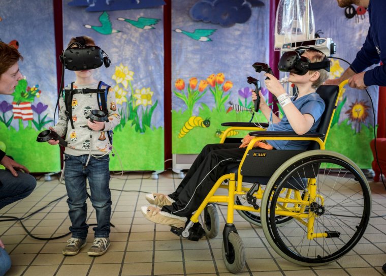 Twee kinderen, een ervan in een rolstoel, hebben een VR-bril op.