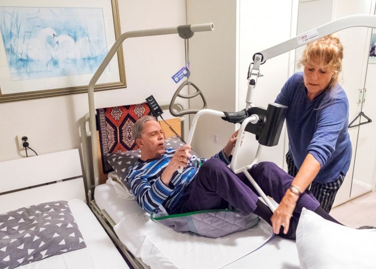 Zorgverlener helpt patiënt in bed met een tilhulp.