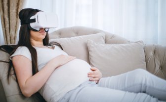 Zwangere vrouw hangt op de bank met VR bril