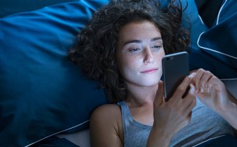 Vrouw in bed kijkt op smartphone met slaap app