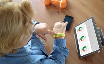 Vrouw kijkt naar tablet met data van haar sensor armband