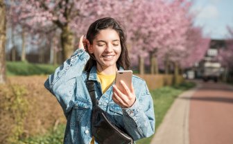 Vrouw op straat bekijkt mantelzorg app op smartphone