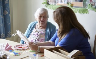 jonge vrouw helpt oudere vrouw met knutselen
