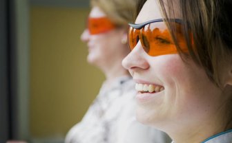 Twee vrouwen staan naast elkaar met de oranje bril op