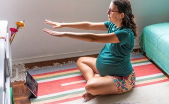 Zwangere vrouw doet fysio oefeningen met een ipad