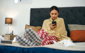 Zieke vrouw in bed thuis kijkt naar herstel app op smartphone