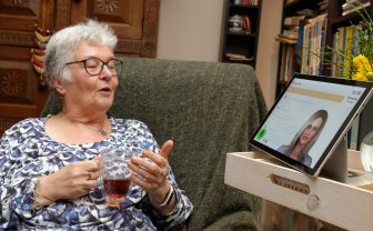Oudere vrouw praat met virtuele assistent Anne op beeldscherm.