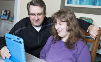 Man zit met iPad naast vrouw met verstandelijke beperking 