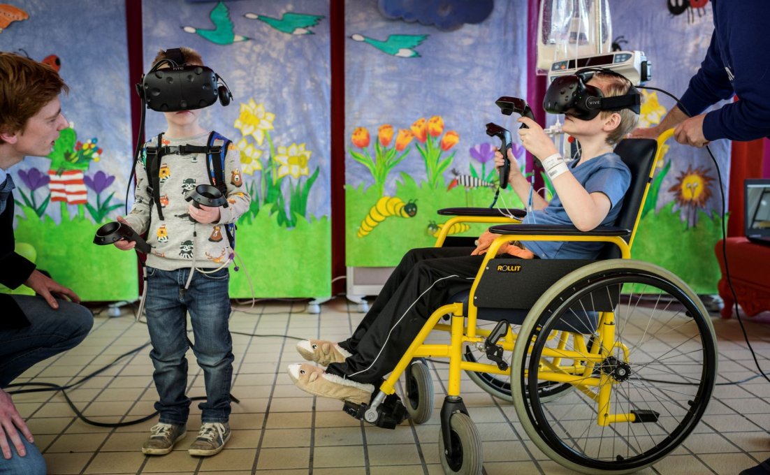 Twee kinderen, een ervan in een rolstoel, hebben een VR-bril op.