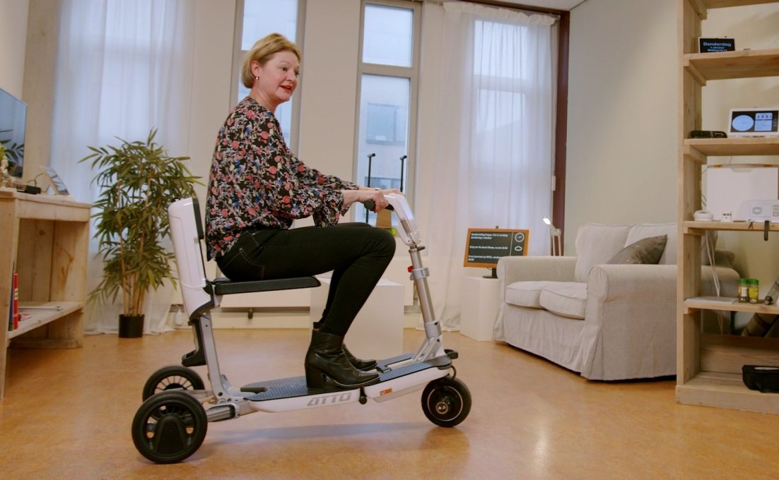 Vrouw rijdt rond in huis op opvouwbare scootmobiel