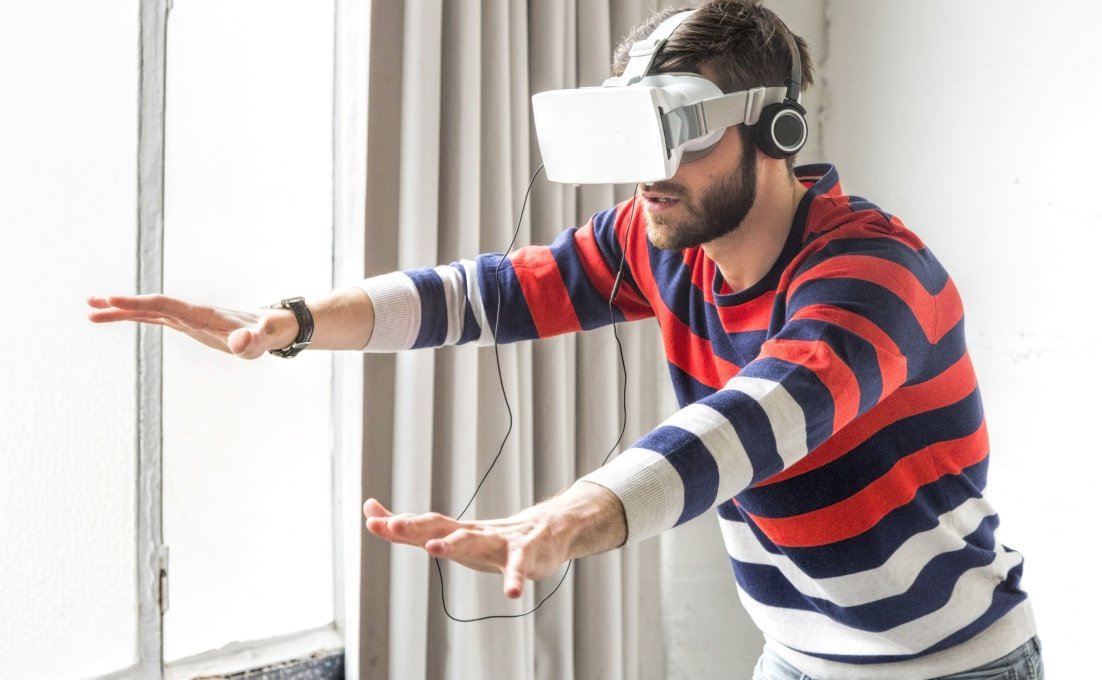 Man met VR bril probeert met handen te voelen wat hij ziet