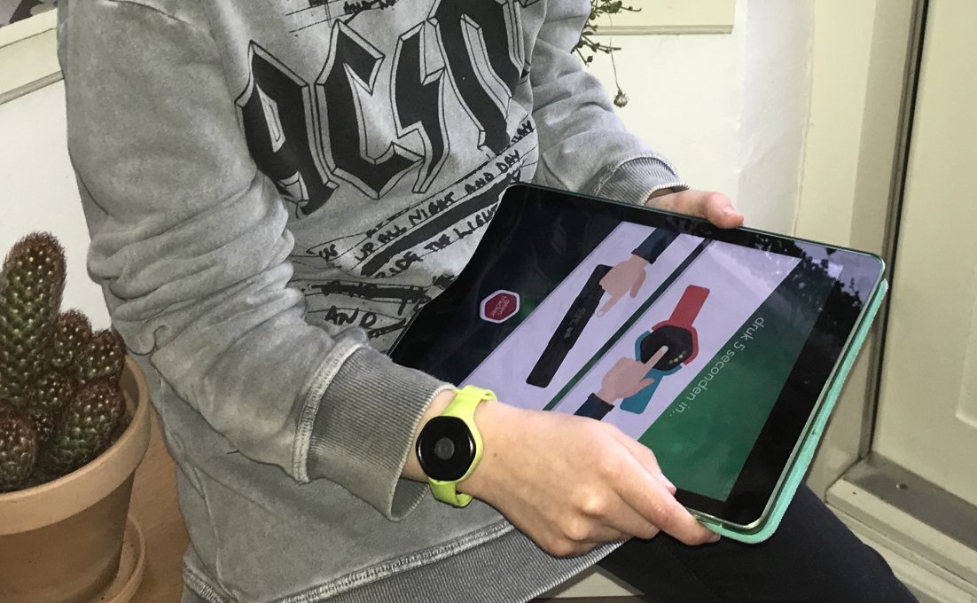 Kind draagt Boosth armband en houdt tablet vast