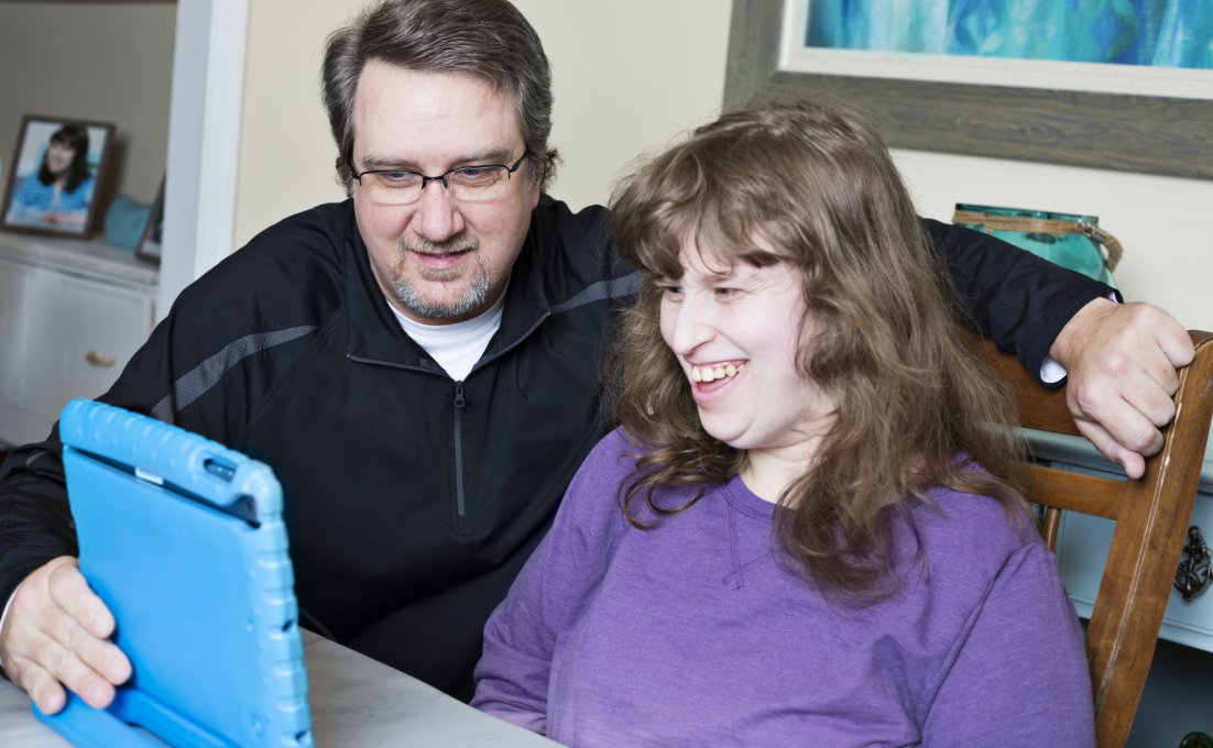 Man zit met iPad naast vrouw met verstandelijke beperking 