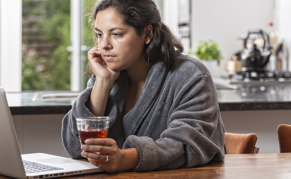 jonge vrouw zit achter haar laptop met kopje thee