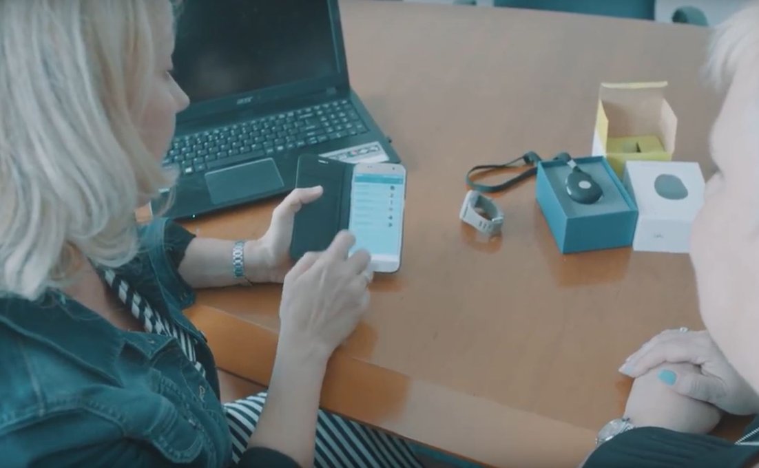 Vrouw laat de producten zien die bij virtuele thuiszorg horen, de app, de alarmering, het horloge
