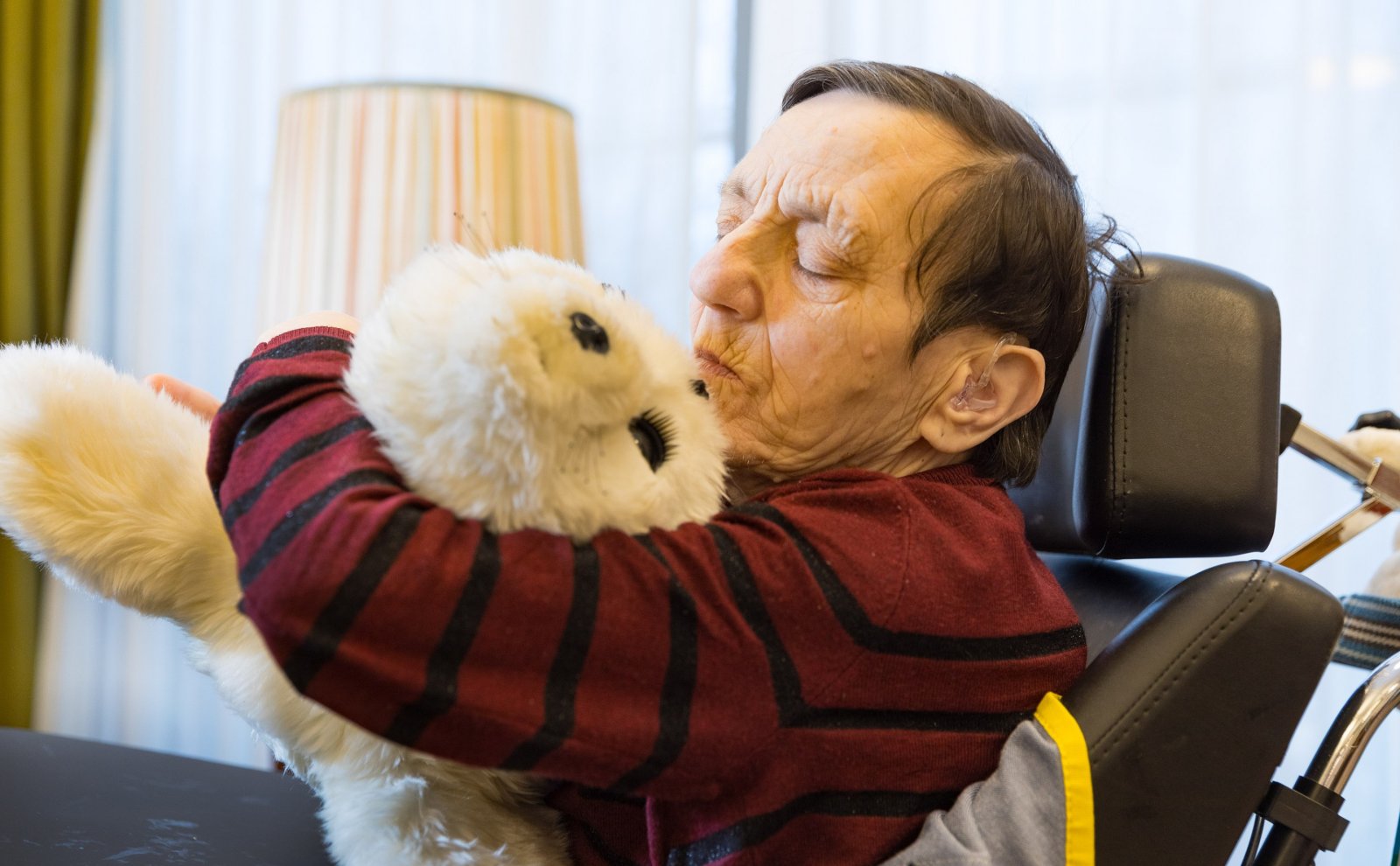 Oudere man knuffelt zeehond Paro, een robot in de zorg 