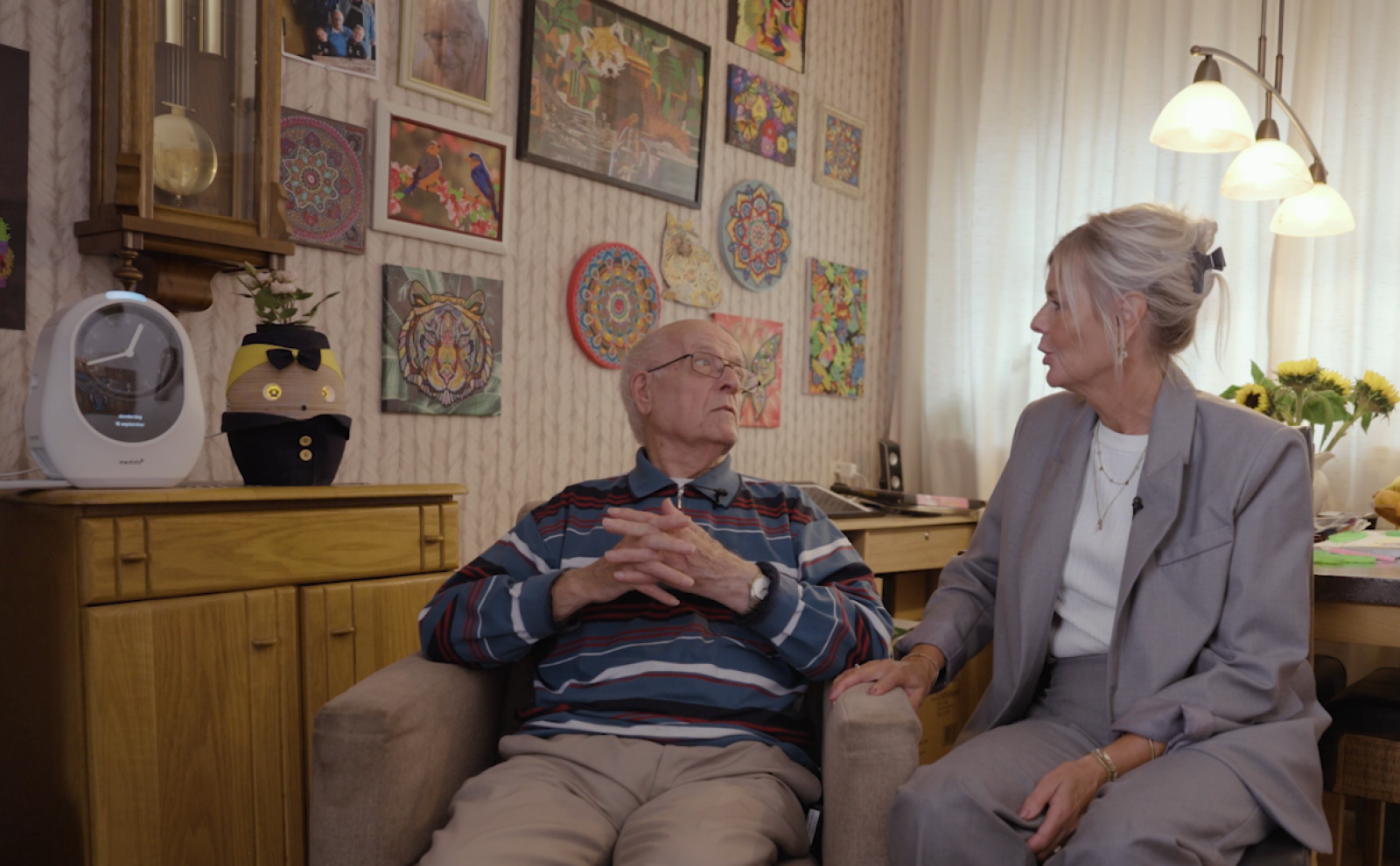 Cliënt en zorgmedewerker zitten naast elkaar in de woonkamer van cliënt